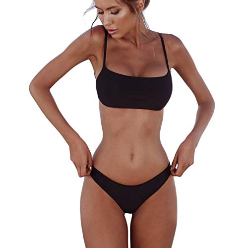 Modelo exhibiendo bikini negro en la playa, mostrando curvas femininas y diseño de bikini minimalista