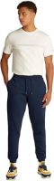 Modelo masculino viste pantalones de chándal Tommy Jeans en color azul marino con camiseta blanca en vista frontal