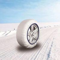 Calcetín de nieve blanco instalado en una rueda sobre una carretera nevada, ideal para mejorar la tracción en condiciones de nieve